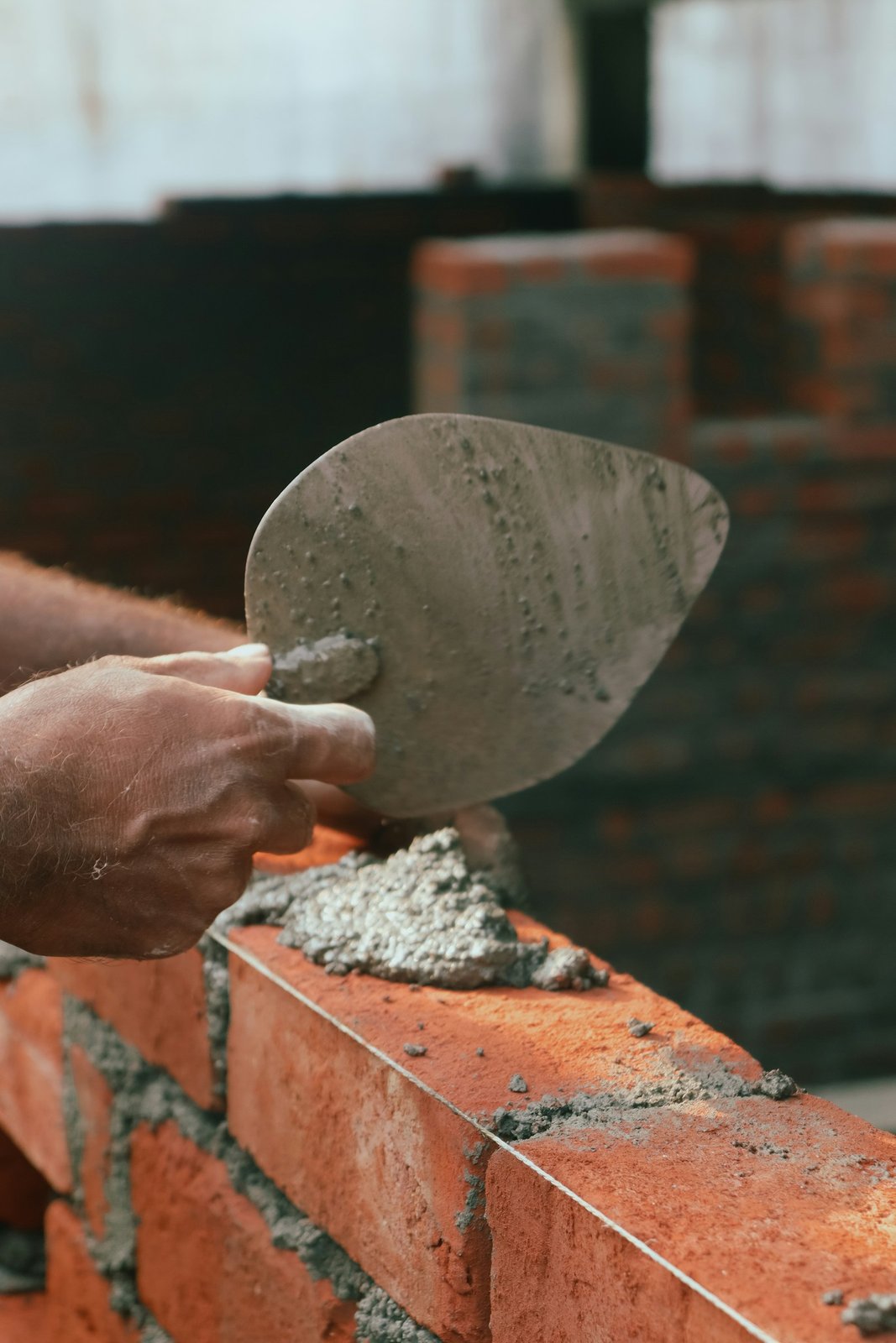 Mason laying brick with mortar and a trowel